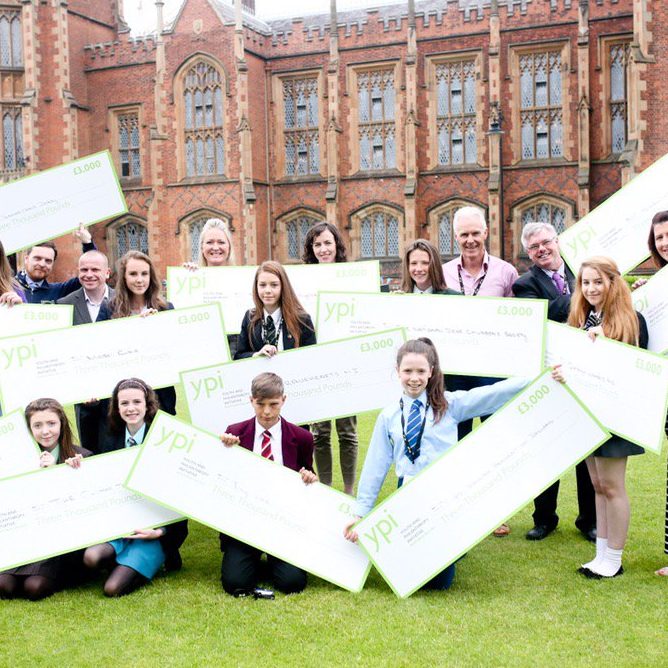 Un groupe d’élèves en Irlande du Nord tenant des chèques géants sur une pelouse