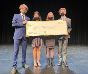 4 students holding a giant cheque on stage