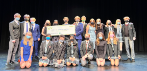 group photo with four students holding giant cheque on stage